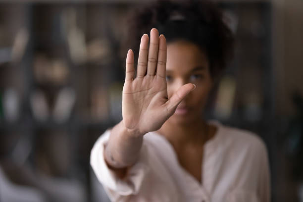 Serious african american woman protesting against bullying. Close up focus on female mixed race palm hand showing stop sign, serious african american woman protesting against bullying in society, sexual or racial discrimination, denying family abuse indoors. harassment stock pictures, royalty-free photos & images