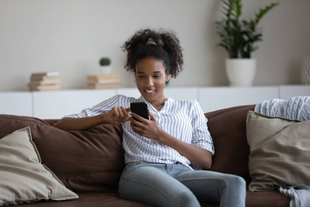istock Relaxed young african woman using smartphone applications at home. 1320498058