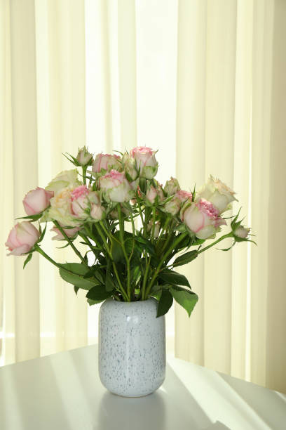 istock Vase with bouquet of roses on white table 1320500170