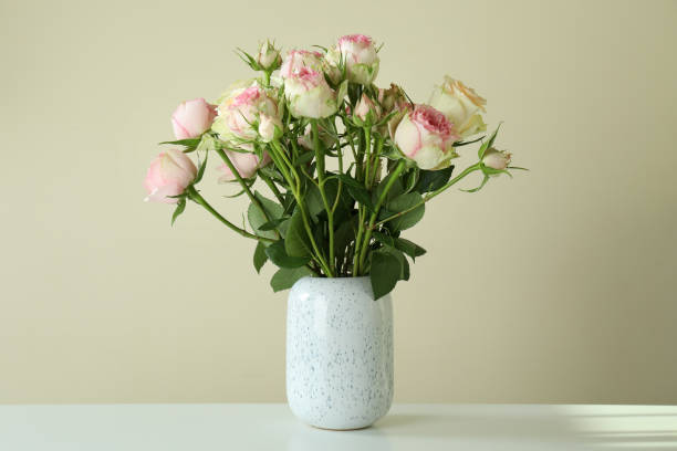 istock Vase with bouquet of roses on white table 1320500396
