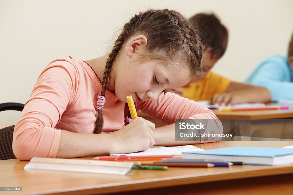 Girl writing Portrait of lovely girl writing in copybook with schoolboys on background Boys Stock Photo