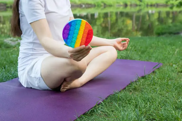 Photo of A woman meditates in nature and eats a reusable bubble wrap pop it antistress toy.