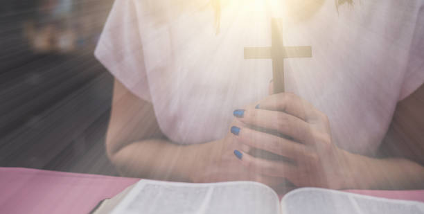 istock a cross is held in hands with the opened bible 1320505601