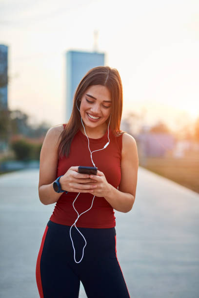 istock Modern young woman with cellphone making pause during jogging exercise. 1320508292