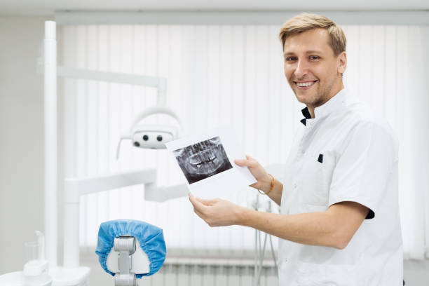 istock Dentist holds a photo of teeth in his hands while explaining 1320510921