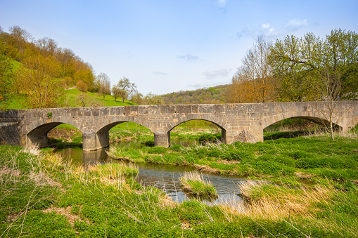 Bibury, flowers stone bridge with flowers near Arlington Row in the England Cotswolds one of the most beautiful villages in the England countryside, UK