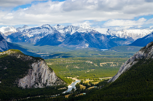 View of Banff from top of Sulphur mountain during day of springtime.\nBehind are Mount Cascade and Mount Tunnel.