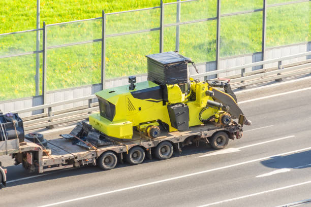 istock Truck with a long trailer platform for transporting heavy machinery, loaded tractor without wheels and bucket. Highway transportation. 1320517869