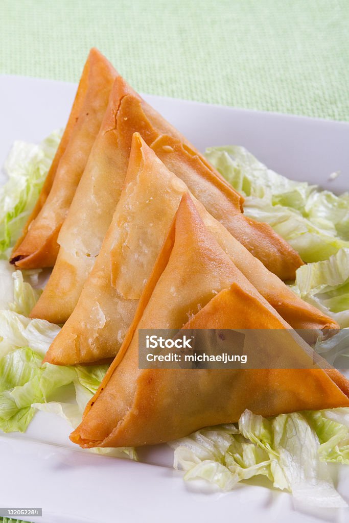 Four samosa served on a white plate  Samosa on plate with lettuces  Appetizer Stock Photo