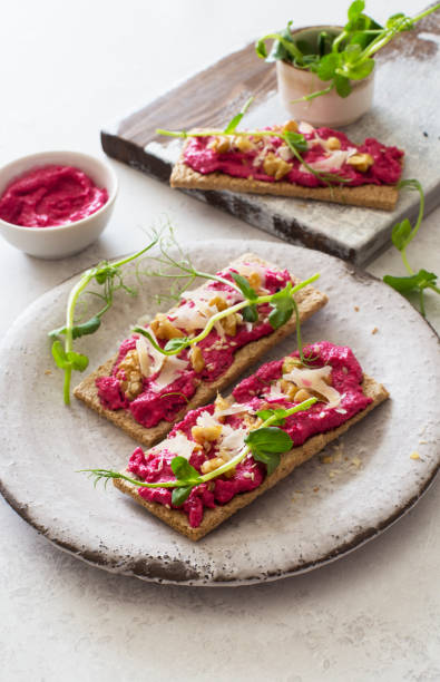 Open sandwiches with beetroot hummus, parmesan cheese and walnuts stock photo