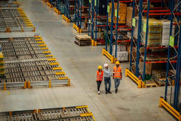 istock Warehouse employees walking through shelves and talking 1320526129