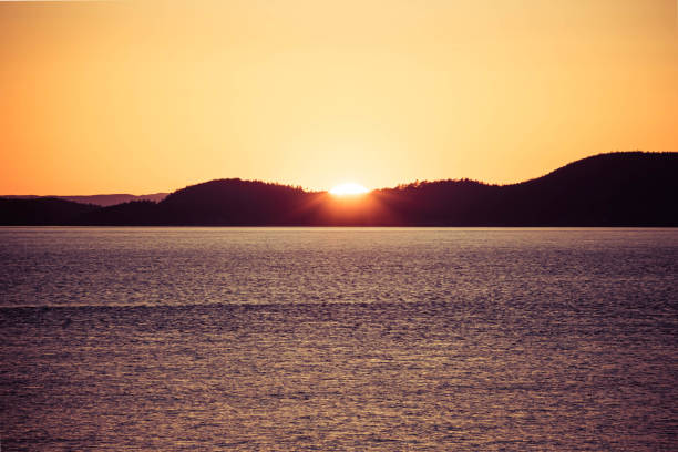 istock A distant sunset over the ocean and hills of a distant island 1320527191