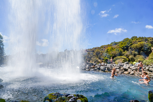 The tourists are playing under the Taranaki Falls in Tongariro National Park, Manawatu-Wanganui, New Zealand.