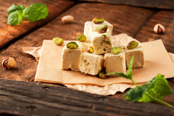 Walnut halva with pistachios on parchment paper on a wooden background. Traditional oriental dessert Chekme. Natural vegan sweets. Rustic style Walnut halva with pistachios on parchment paper on a wooden background. Traditional oriental dessert Chekme. Natural vegan sweets. Rustic style. oriental food stock pictures, royalty-free photos & images