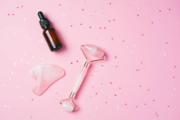 istock Roller and gua sha massage scraper and cometic product on a pink background 1320534470