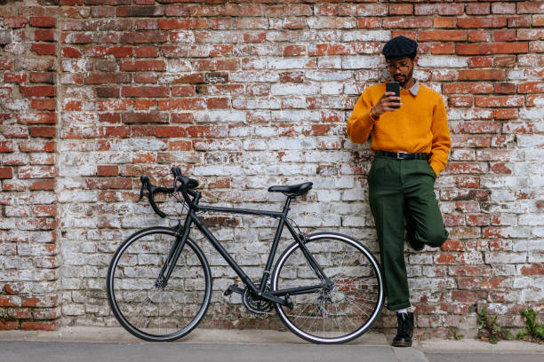 Urban cyclist resting on the street and using phone