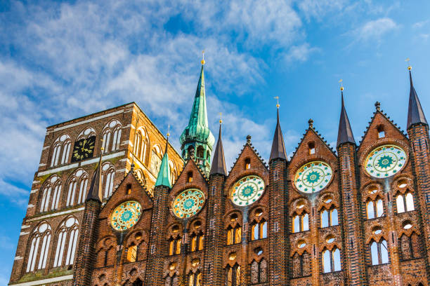 Façade of the historic town hall in Stralsund in the style of North German brick Gothic with the Nikolaikirche in the background.