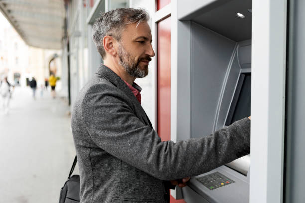 istock Businessman using card at an ATM in city 1320543759