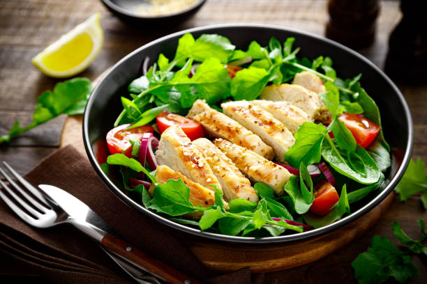 istock Grilled chicken breast and salad. Fresh vegetable salad with tomato, arugula, spinach and grilled chicken meat in bowl, healthy food. 1320546020