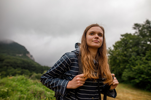 Beautiful young woman hiking on mountain during overcast autumn day