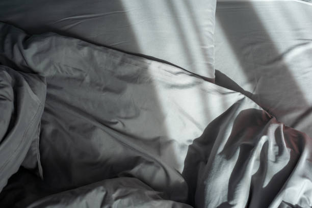 istock Comfortable bed with pillows and blanket in shady room 1320548472