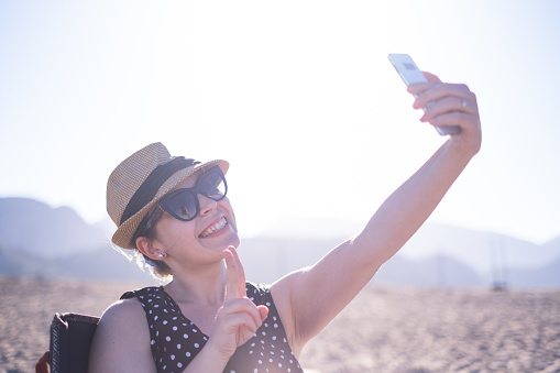 Young woman taking selfie on the sandy beach.