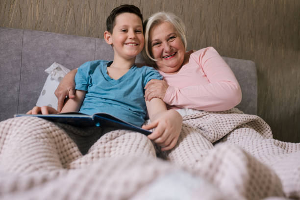 istock Boy and his granny are lying on bed, reading bedtime stroy. 1320550902