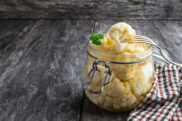 Pickled cauliflower in glass jar on rustic wooden table