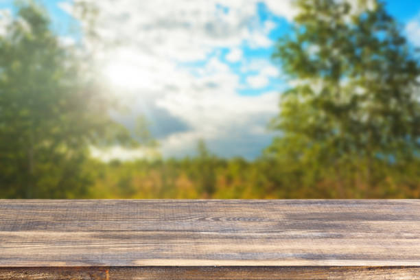 istock wood table top against blurred sky and trees background 1320551572