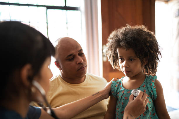 Pediatrician doctor listening to patient's heart at home during home visit