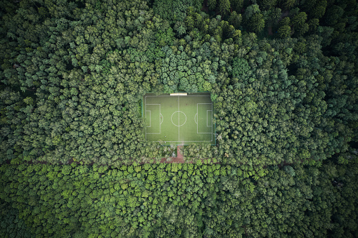 Aerial top down view of a soccer field in the dense forest. Camera is looking down