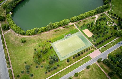 Aerial of soccer field beside a small lake. Green lawn around