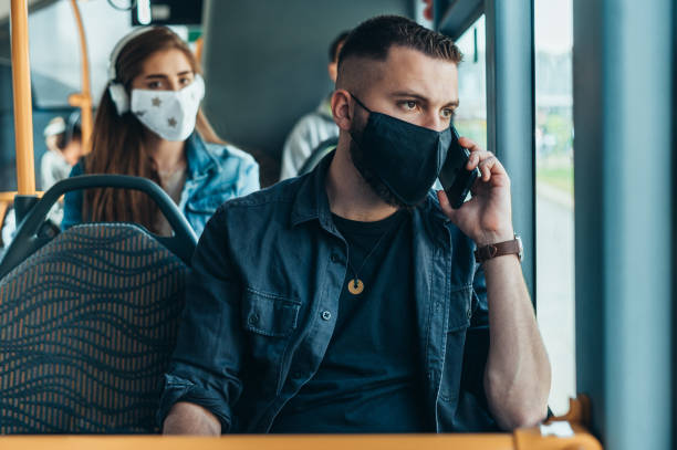 young man wearing protective mask while riding a bus - bus riding public transportation businessman imagens e fotografias de stock