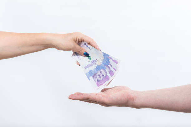 woman's hand depositing Colombian currency banknotes on man's hand, isolated on white woman's hand depositing Colombian currency banknotes on man's hand, isolated on white colombian peso stock pictures, royalty-free photos & images