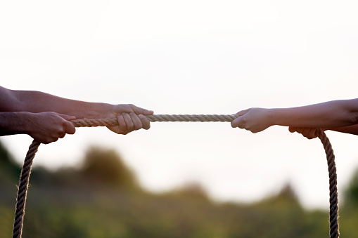 People pulling rope in opposite directions at office