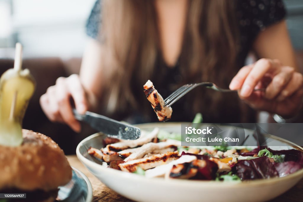 Lunch time Women in the pub eating chicken salad with fork and knife. Pub Stock Photo
