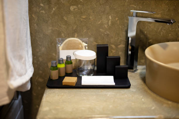 White folded towels and glass bottle on white table with copy space on blurred bathroom background. For product display montage.