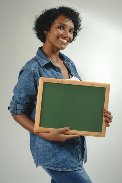 istock Happy black young woman holding empty board to write on 1320585845