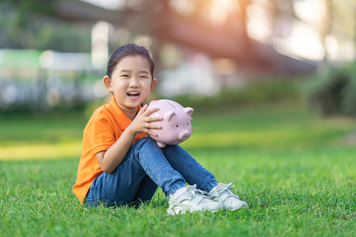 Little Girl Holding Piggy Bank on the Grass