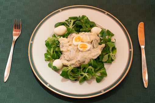 Viennese Fish Salad with Pickled Herring called Heringsschmaus, Wiener Heringssalat or Fischsalat in Austria, Served with Lamb's Lettuce and Quail Eggs
