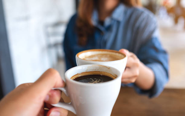 una mujer y un hombre parpadeando tazas de café juntos en el café - café bebida fotografías e imágenes de stock