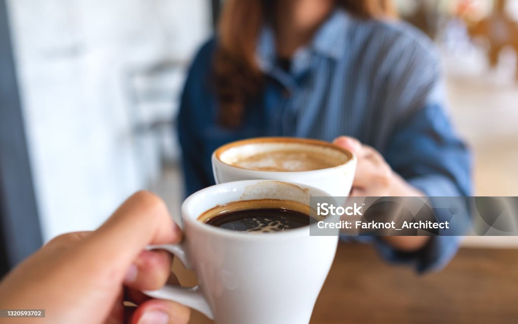 a woman and a man clinking coffee cups together in cafe Closeup image of a woman and a man clinking coffee cups together in cafe Coffee - Drink Stock Photo