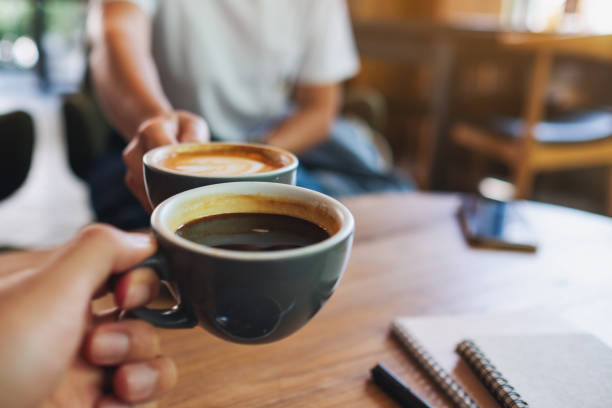 istock a man and a woman clinking white coffee mugs in cafe 1320593705