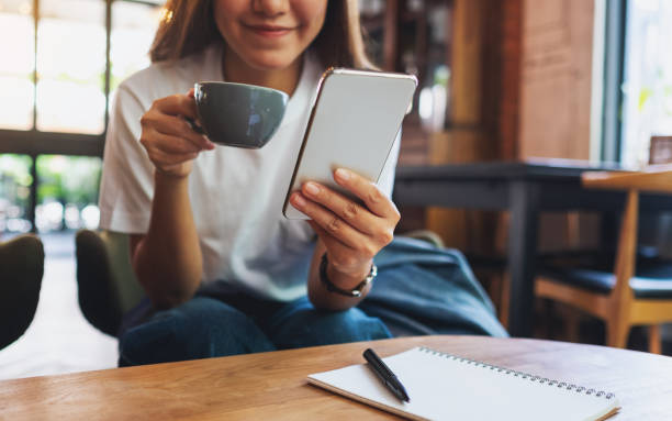 istock a beautiful young asian woman holding and using mobile phone while drinking coffee 1320593717