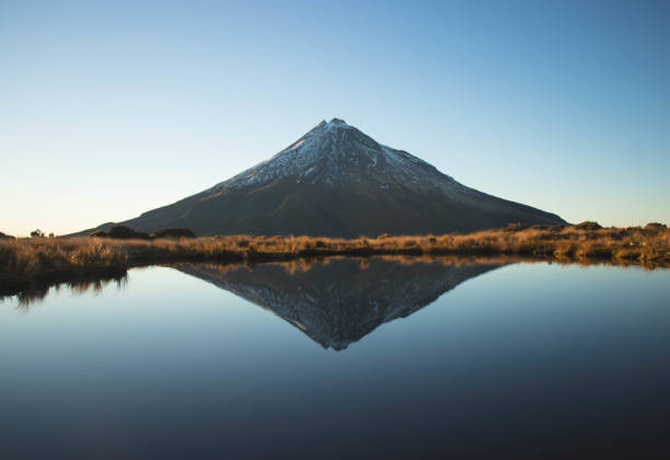 Mount Taranaki Pouakai Circuit Reflective Tarn at Sunrise - New Plymouth, North Island, New Zealand Shot of Mt. Taranaki reflecting on the surface of a tarn. On the hiking track called Pouakai Range Tramping Tracks/Pouakai Crossing. It is located near New Plymouth, Taranaki Region, North Island, New Zealand. mirror lake stock pictures, royalty-free photos & images