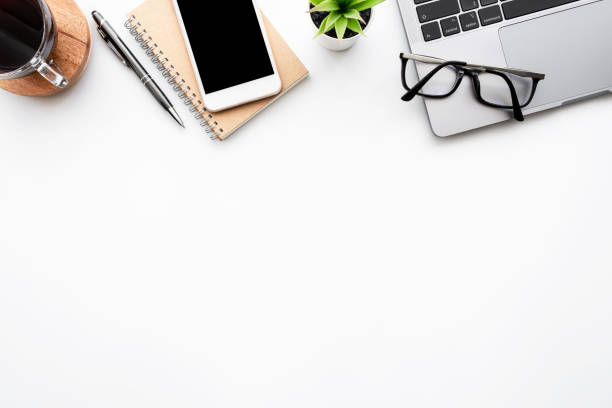 istock White office desk table with laptop computer, smartphone with blank screen, cup of coffee and office supplies. Top view with copy space, flat lay. 1320599179