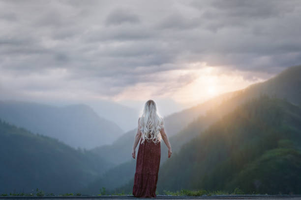 istock Woman looking out at the mountains with sky above. 1320601347