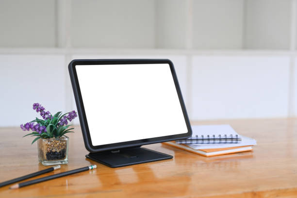 istock Digital tablet with blank screen, notebook and house plant on wooden desk. 1320602217