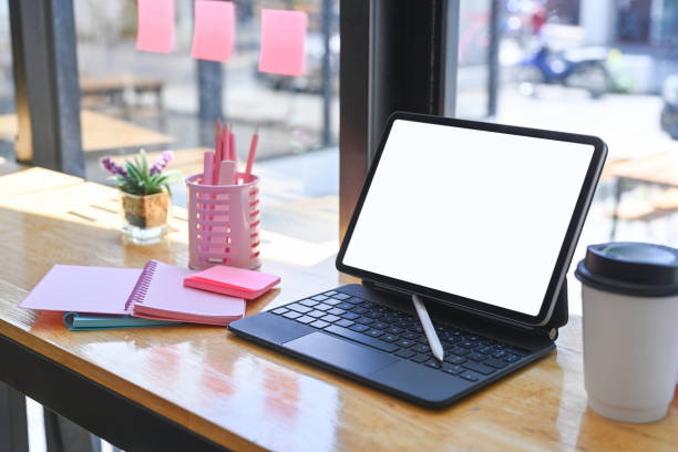 istock Mock up computer tablet, cup of coffee, notebook and pencil holder on wooden bar. 1320602271