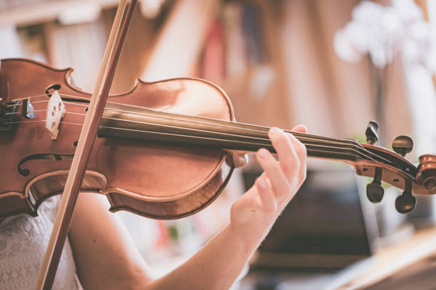 istock Practicing classical music and violin concept: Young girl happily plays on her violin 1320604134